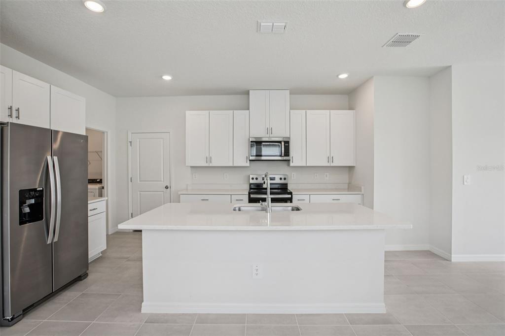 1820 Brekey Way Zephyrhills, FL 33541 - Photo 14 of 41 a white kitchen with a sink a stove a refrigerator and white cabinets