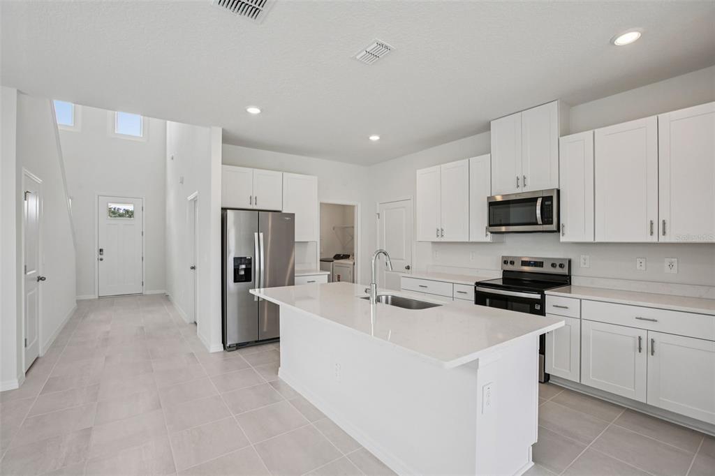 1820 Brekey Way Zephyrhills, FL 33541 - Photo 19 of 41 a kitchen with stainless steel appliances a refrigerator stove microwave and white cabinets