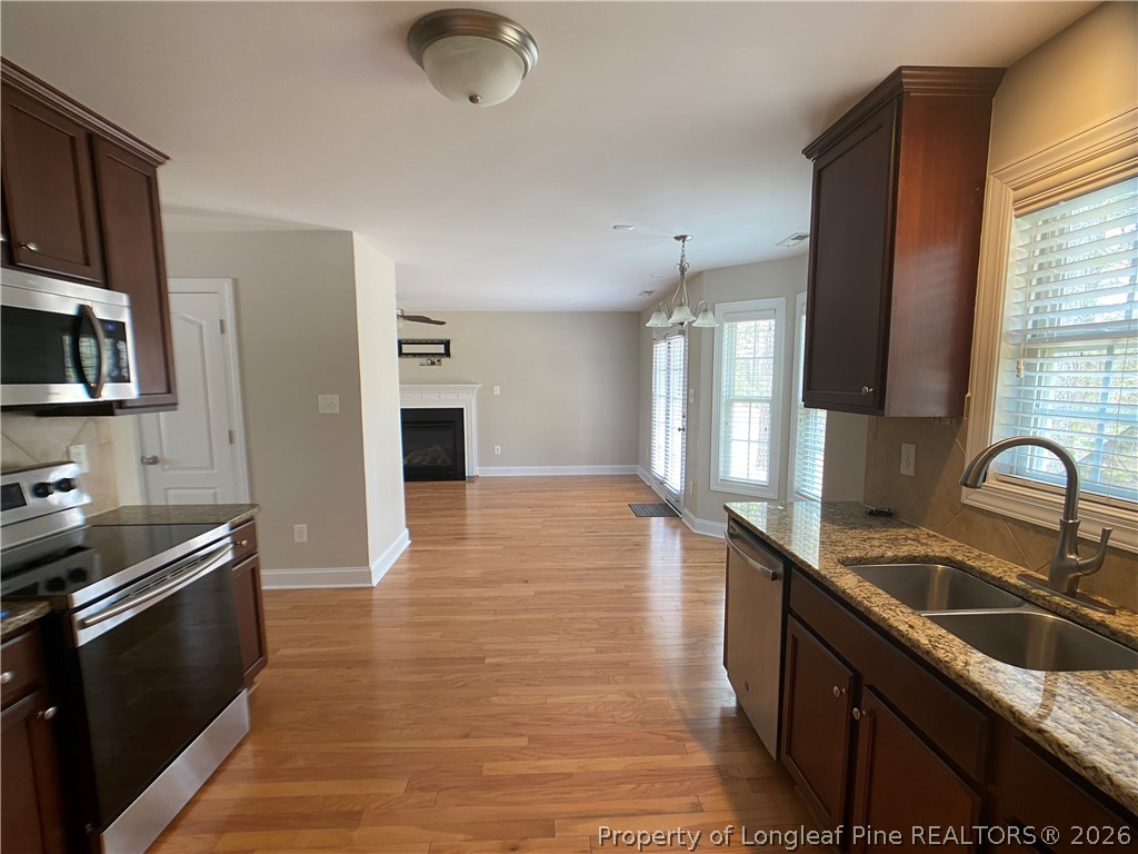 56 Orchard Falls Drive Spring Lake, NC 28390 - Photo 14 of 24 a kitchen with granite countertop a sink wooden floor and stainless steel appliances