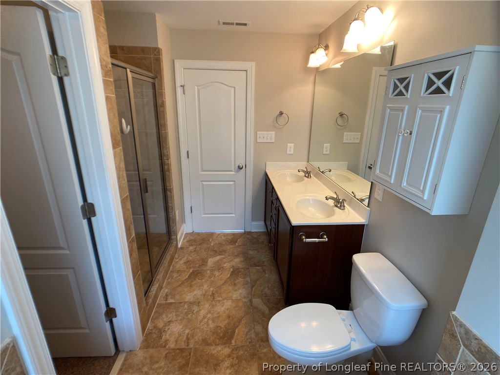56 Orchard Falls Drive Spring Lake, NC 28390 - Photo 22 of 24 a bathroom with a sink a toilet a mirror and vanity