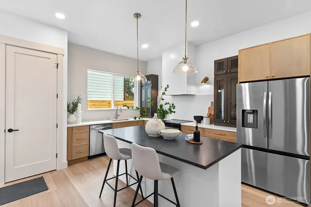 a kitchen with stainless steel appliances a table chairs in it and wooden floors