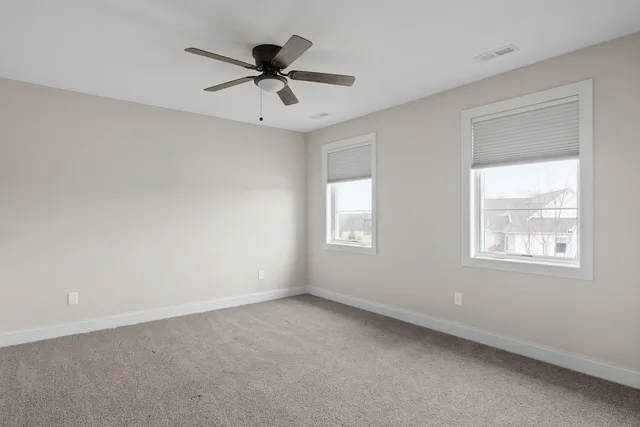 a view of an empty room with cabinet and windows