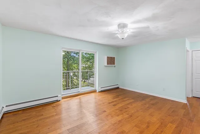 an empty room with wooden floor fan and windows