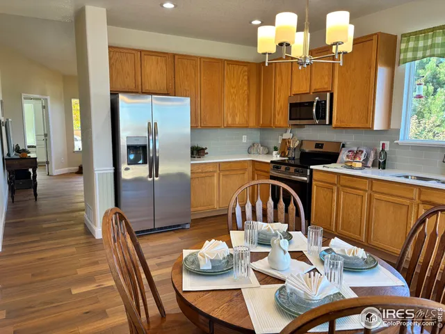 a kitchen with stainless steel appliances a table chairs and a refrigerator