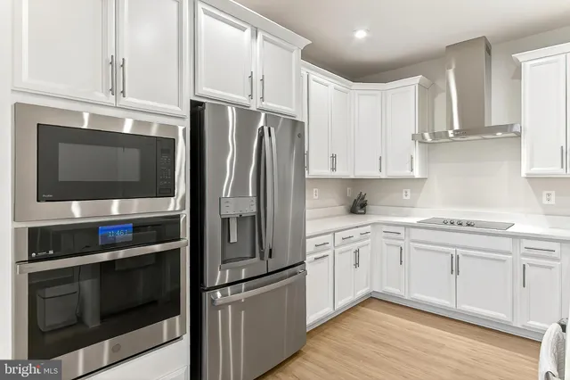a kitchen with white cabinets white appliances sink and dishwasher with wooden floor