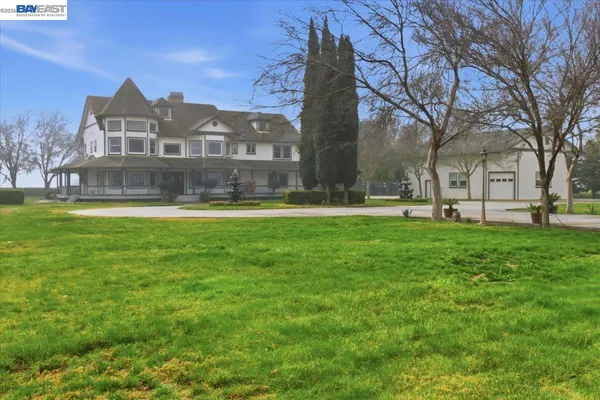 a front view of a building with garden and trees