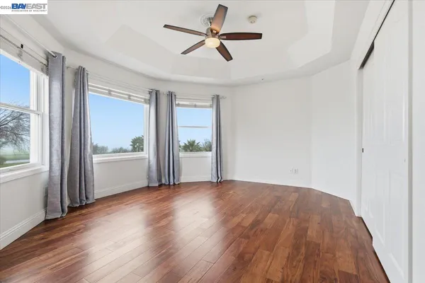 a spacious bedroom with a bed and wooden floor