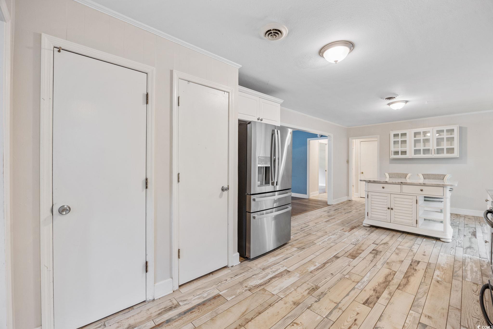 4303 Old Kings Highway Murrells Inlet, SC 29576 - Photo 10 of 34 Kitchen featuring white cabinetry, backsplash, appliances with stainless steel finishes, ornamental molding, and light wood finished floors