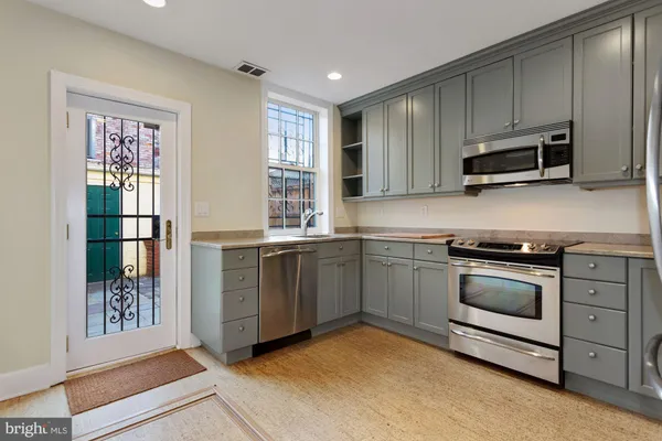 a kitchen with stainless steel appliances granite countertop a stove a sink and a microwave