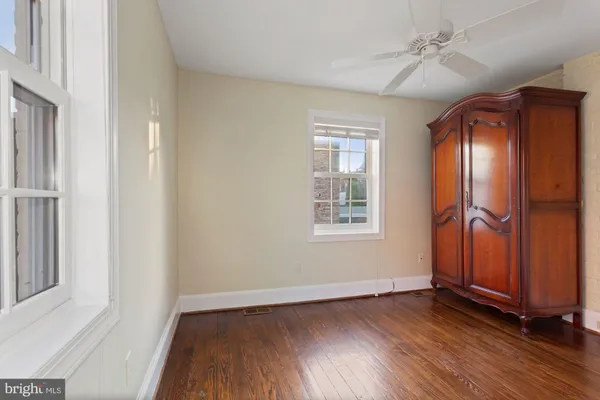 an empty room with wooden floor closet and windows