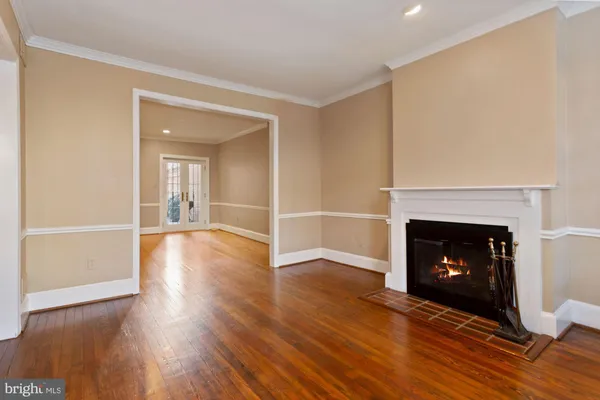 a view of an empty room with wooden floor fireplace and a window