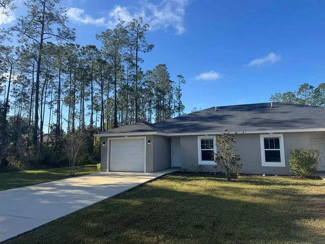 a view of a white house with a yard and large tree