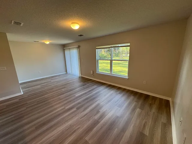 a view of kitchen and empty room with wooden floor