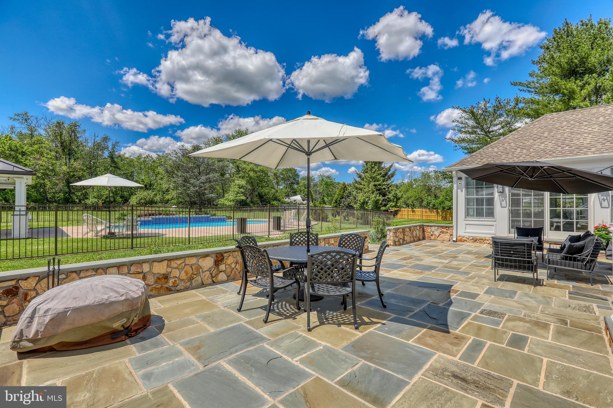 1071 Highland Road Newtown, PA 18940 - Photo 36 of 40 a view of a patio with a dining table and chairs under an umbrella with a barbeque grill and plants