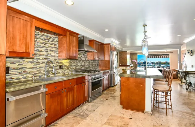 a kitchen with stainless steel appliances granite countertop a stove top oven a sink dishwasher a dining table and chairs with wooden floor