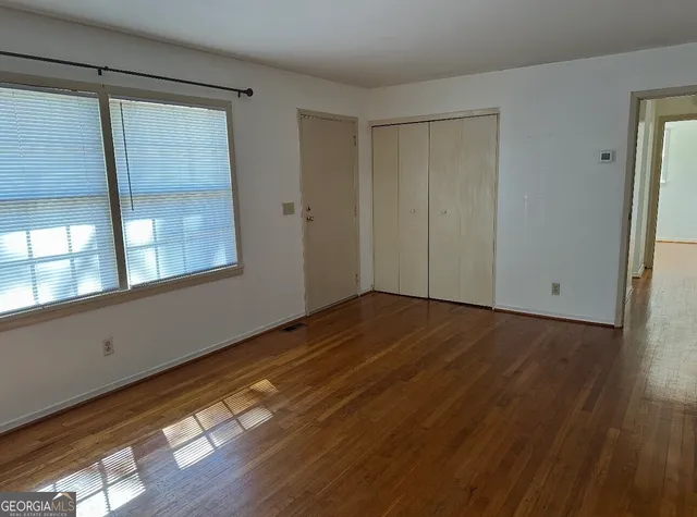 a view of empty room with wooden floor and fan