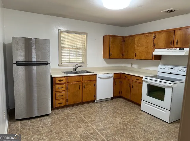 a kitchen with a white stove refrigerator and cabinets