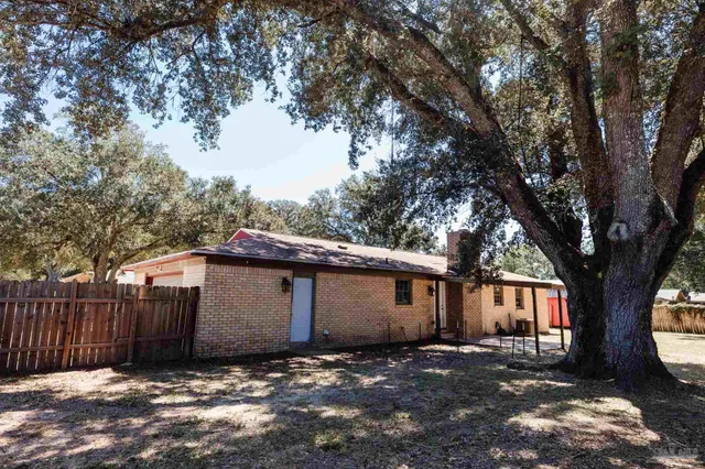 a view of a house with a large tree and wooden fence