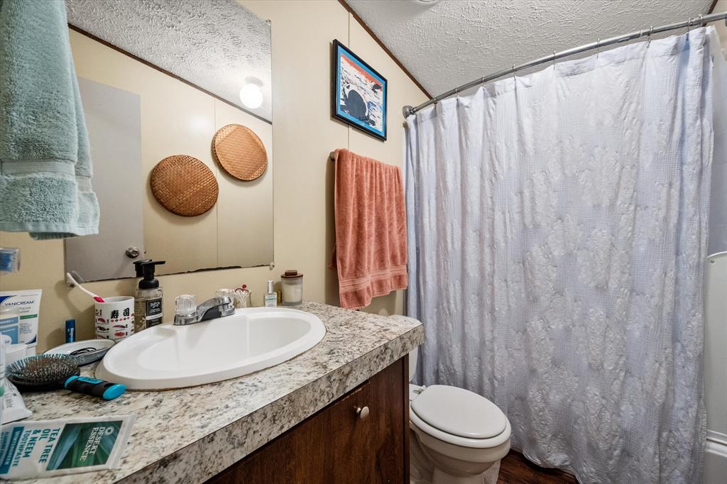 14036 Old Texaco Road Conroe, TX 77302 - Photo 32 of 40 Full bath featuring curtained shower, toilet, vanity, and a textured ceiling