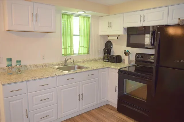 a kitchen with granite countertop white cabinets and stainless steel appliances