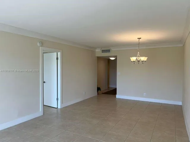 an empty room with chandelier fan and windows