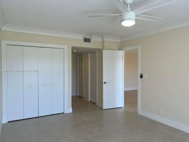 an empty room with closet and a ceiling fan