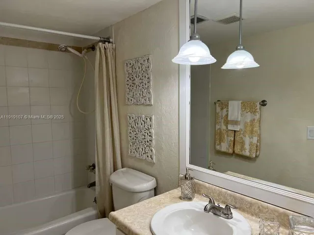 a bathroom with a sink a mirror a toilet and shower