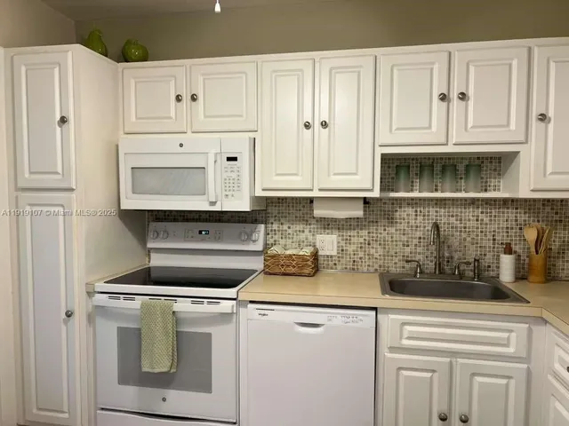 a kitchen with white cabinets and white appliances