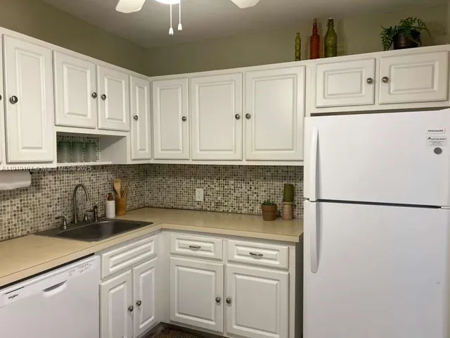 a kitchen with appliances a refrigerator and cabinets