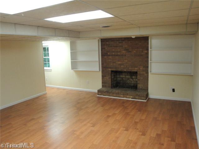 398 Farmstead Road Winston-Salem, NC 27107 - Photo 10 of 16 Den/Family/Great Room. This lower level den houses the second wood burning brick fireplace, beautifully finished with laminate floors and painted paneling.