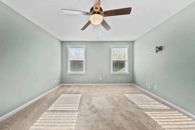an empty room with window and ceiling fan