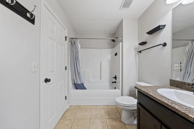 an empty room with a chandelier fan and windows