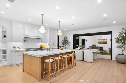 a open kitchen with stainless steel appliances granite countertop a stove a sink dishwasher a refrigerator and white cabinets with wooden floor