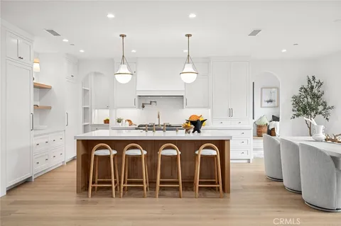 a large kitchen with granite countertop a white stove top oven a sink a dining table and chairs