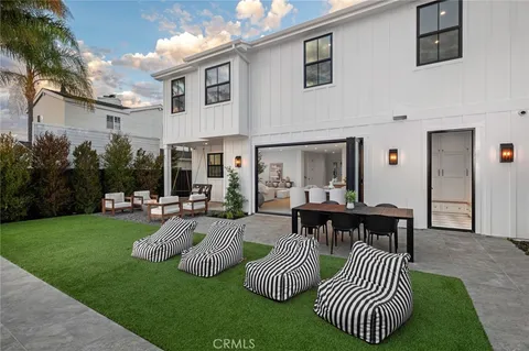 a view of a patio with dining table and chairs with plants and wooden fence