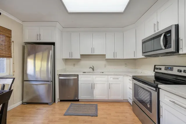 a kitchen with cabinets stainless steel appliances and wooden floor