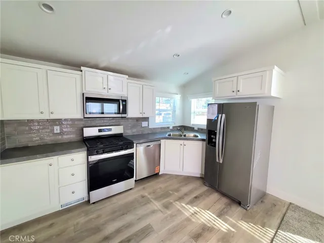 a kitchen with granite countertop a refrigerator stove and sink