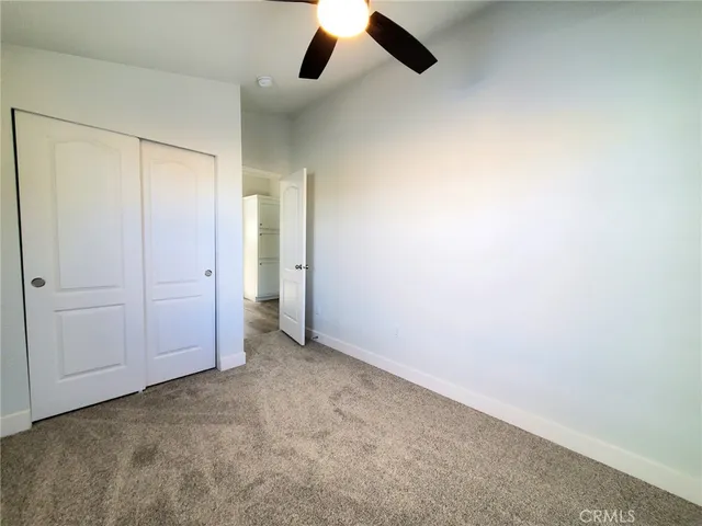 an empty room with a ceiling fan and carpet