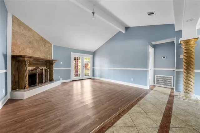 an empty room with wooden floor fireplace and windows