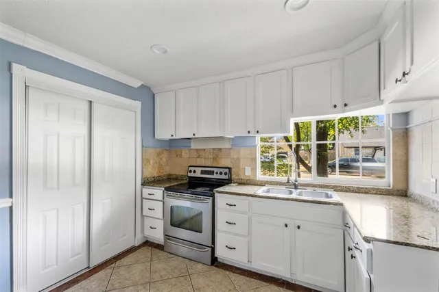 a kitchen with granite countertop white cabinets white appliances and a sink