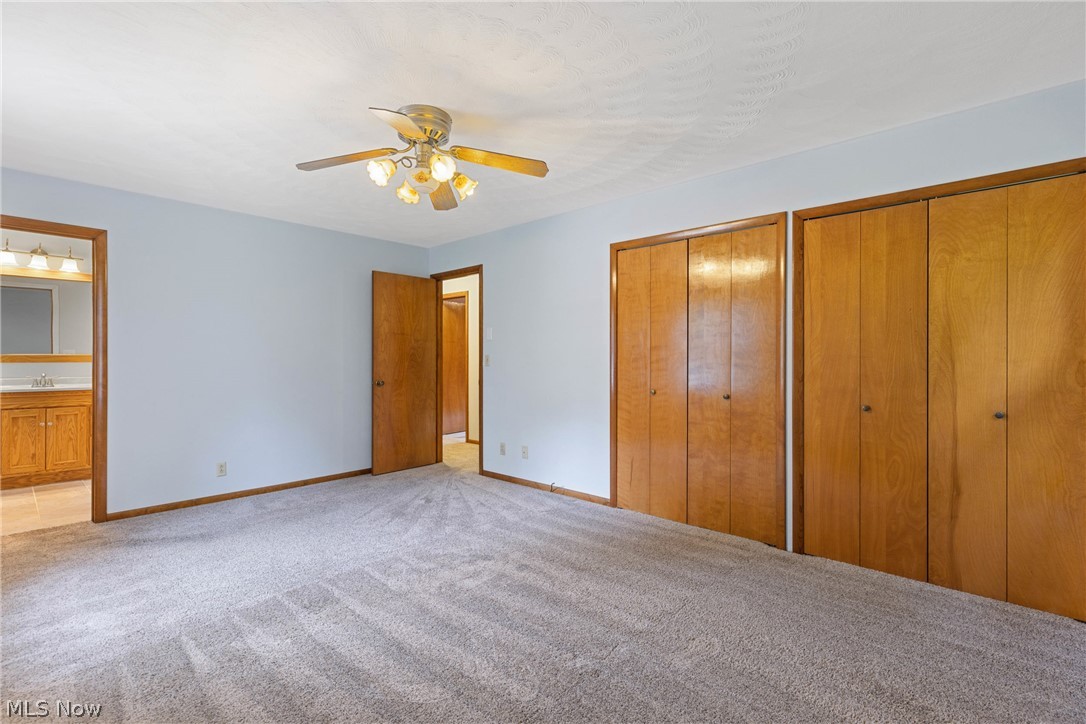 16295 Sperry Road Vermilion, OH 44089 - Photo 18 of 48 Unfurnished bedroom featuring ceiling fan, two closets, light colored carpet, sink, and connected bathroom