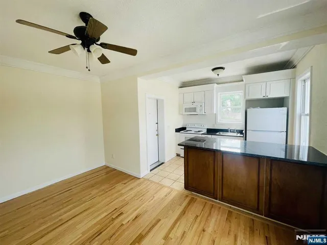 a view of kitchen with wooden floor a sink and a refrigerator