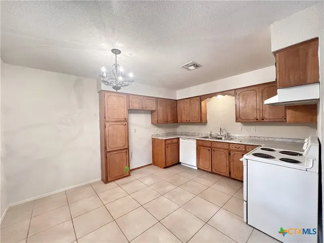 a kitchen with granite countertop a sink stove and refrigerator