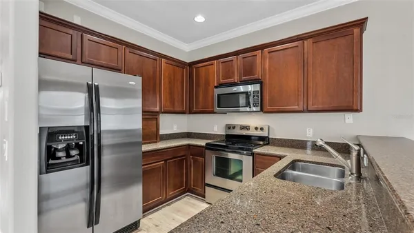 a kitchen with stainless steel appliances granite countertop a refrigerator a sink a stove a microwave and island