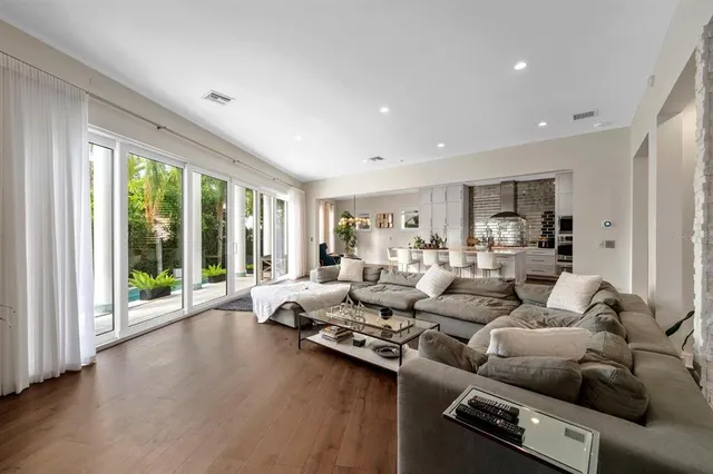 a kitchen with stainless steel appliances kitchen island granite countertop a dining table chairs refrigerator and sink