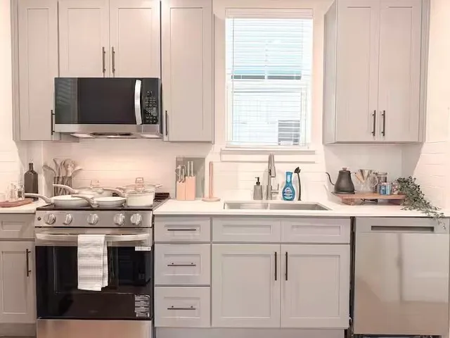 a kitchen with stainless steel appliances a stove a sink and white cabinets