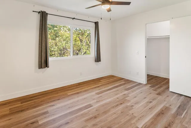 a view of a hallway with wooden floor and a bathroom