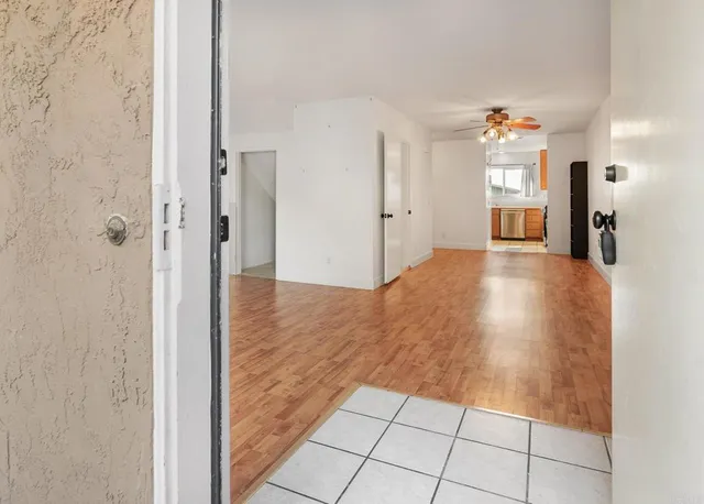 a view of empty room with wooden floor and fan