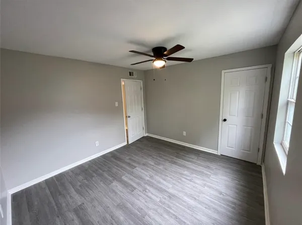 a view of empty room with wooden floor and fan