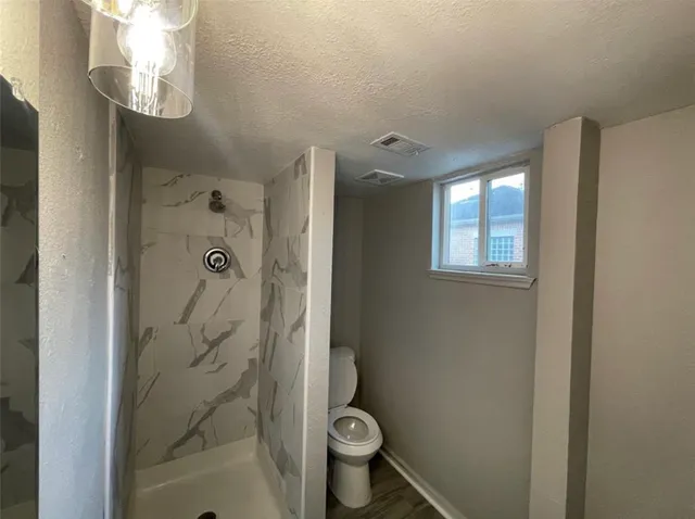 a bathroom with a granite countertop toilet and a shower